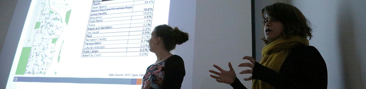 two men in front of a large LCD display