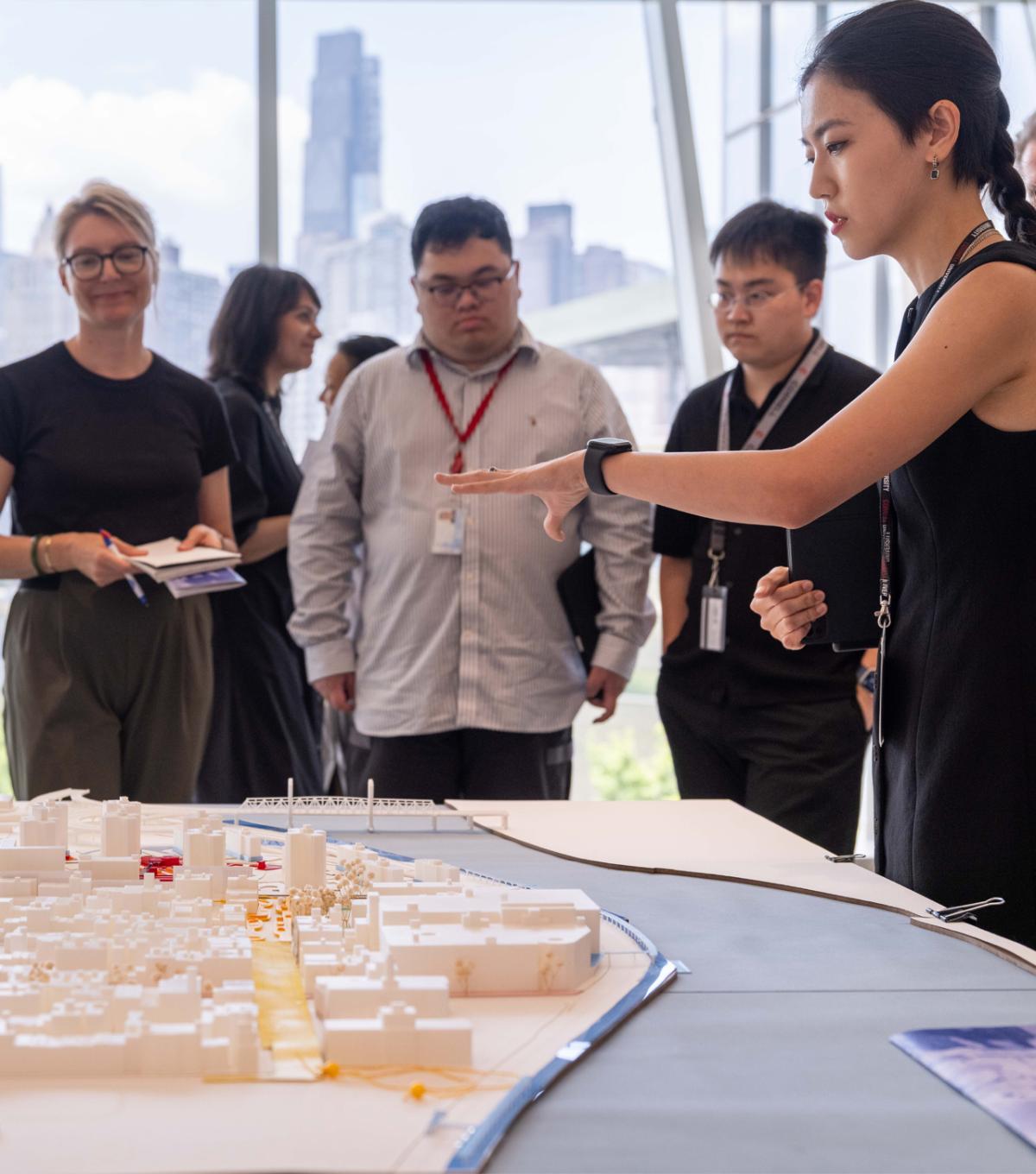 a student discussing their project in front of several other people in a room