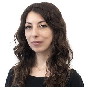 Light-skinned woman with long dark hair wearing a dark shirt