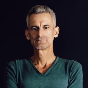 A white male with a green v neck and short grey hair.