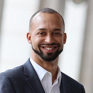 Man smiling in a white collared shirt and navy jacket