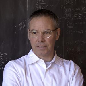 head shot of a white man with close cropped hair in a pink shirt