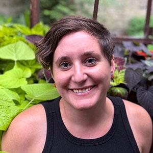 Woman with short brown hair and a black tank top smiles at the camera