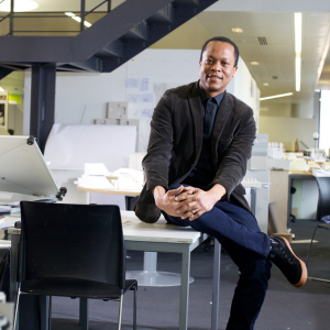 A man sitting on a desk and smiling at the camera