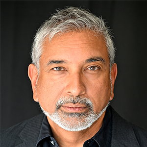 A man with grey hair and grey facial hair looking directly at the camera with a neutral expression on his face.