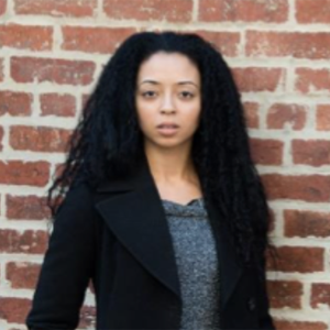 woman with long dark hair and grey shirt and blazer