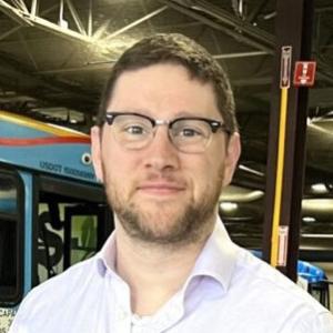 A man wearing glasses and smiling in the TCAT bus garage