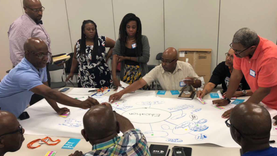 People sitting at a table working together on a large piece of paper.