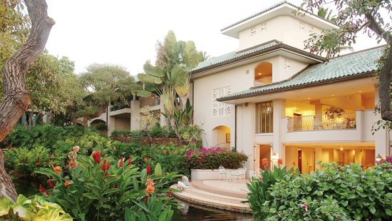 Large white house with steps down to a pond surrounded by thick landscaping