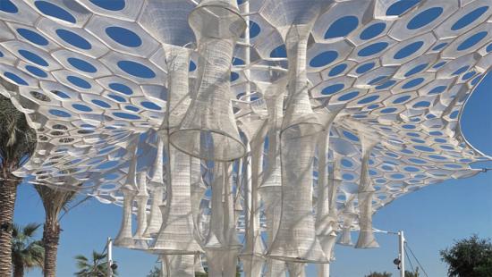 White trumpet shapes descend from perforated white canopy against blue sky.