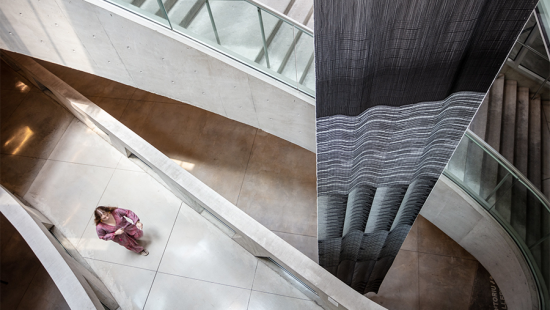 Aerial view of hanging black and white tapestry with woman passing by.