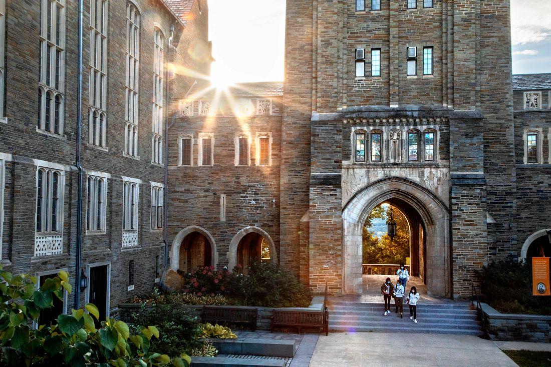 People walking out of a building's archway with the sign shining through.