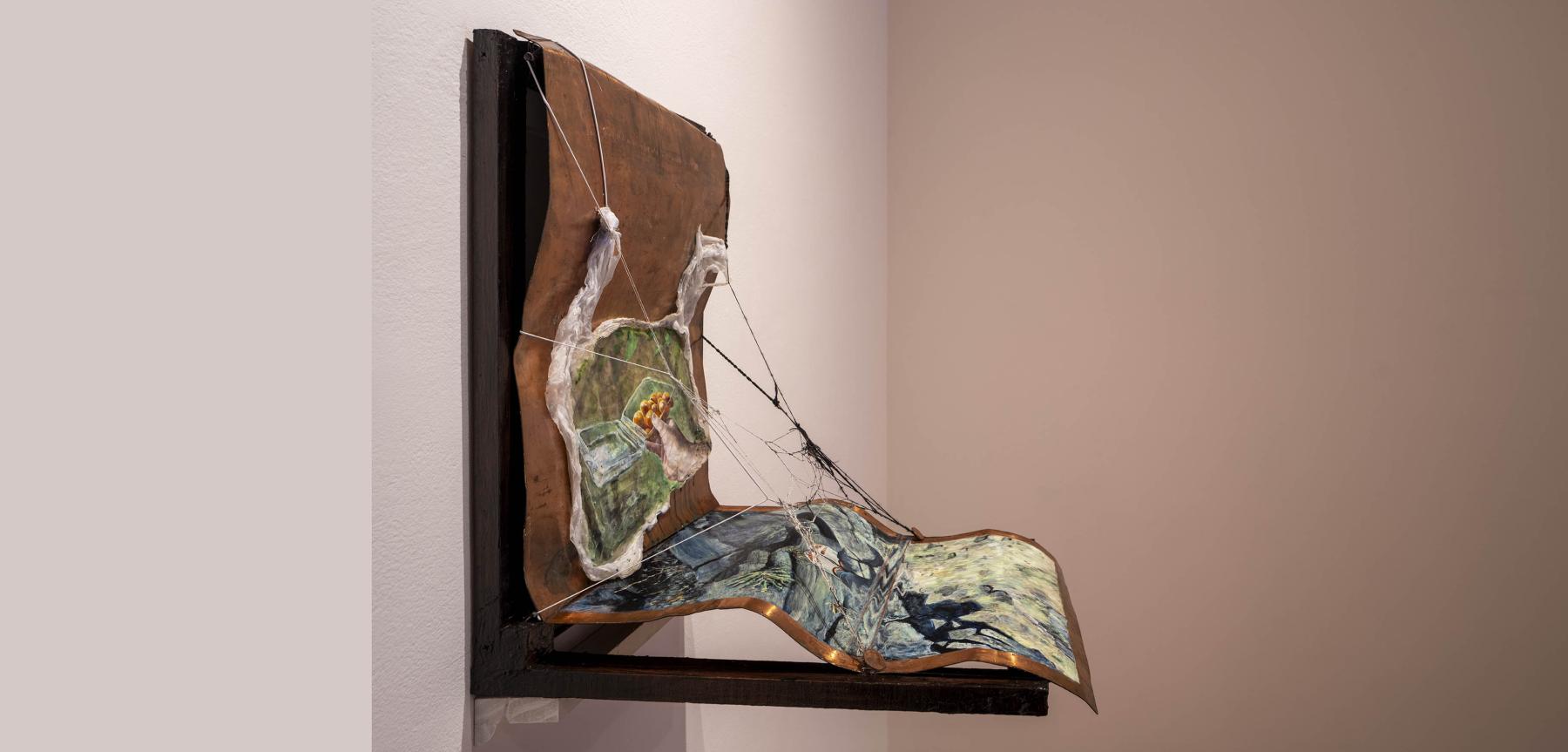 Abstract small painting folded in a ninety degree angle on a dark wood platform.