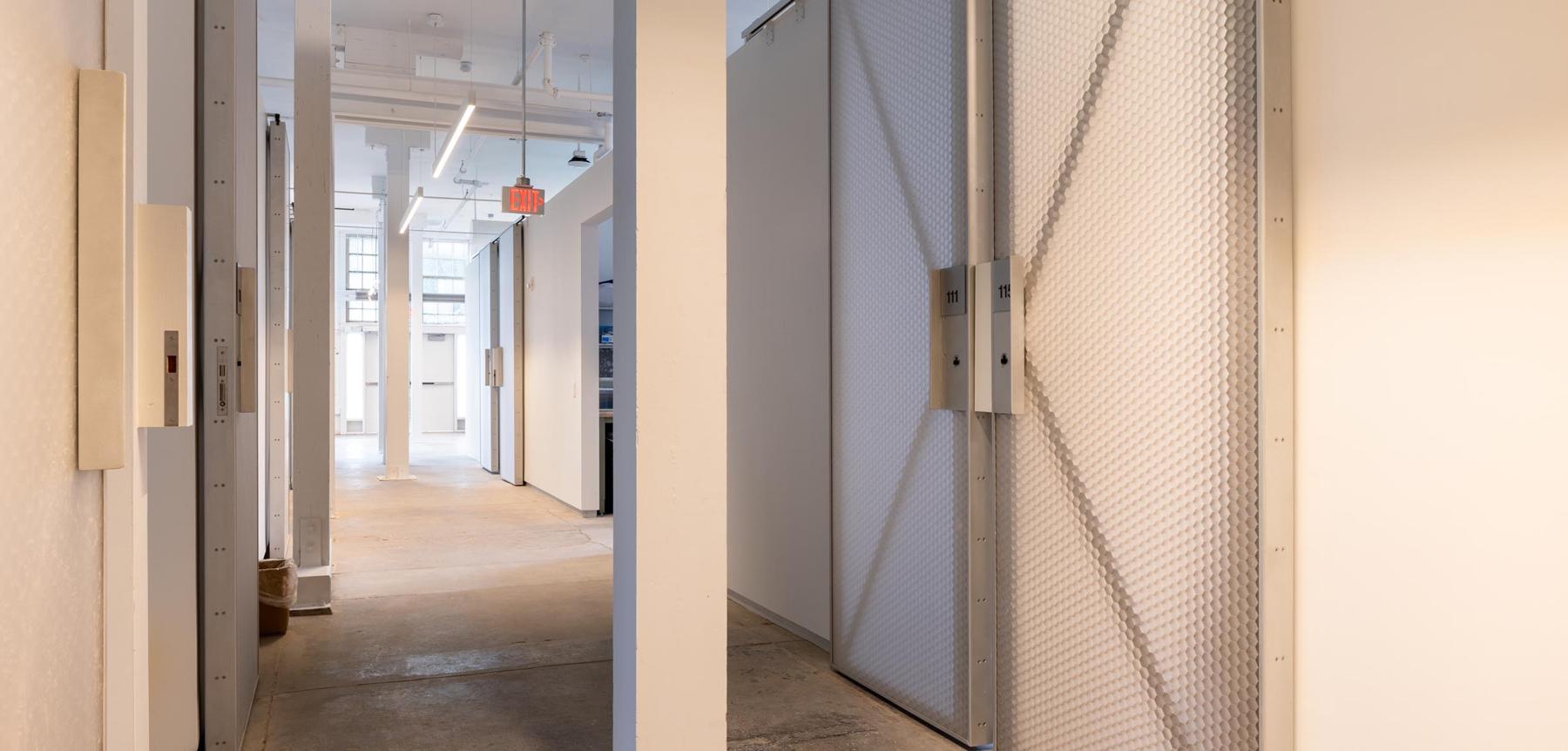 White hallway with large opaque grey doors shut.