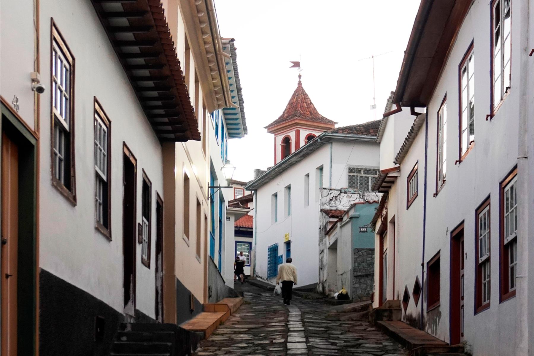a narrow street lined with white painted buildings with tile roofs