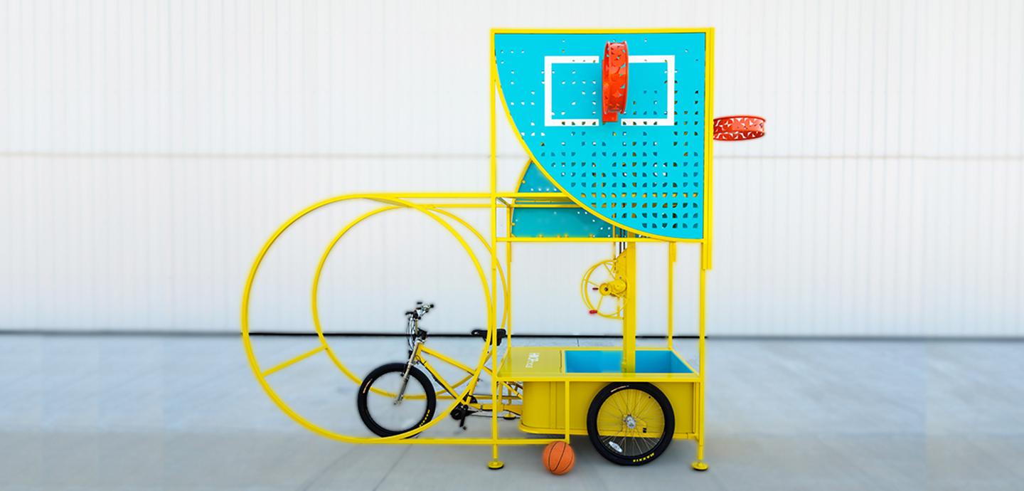 A bright yellow and blue sculpture that combines a bicycle with a basketball hoop.