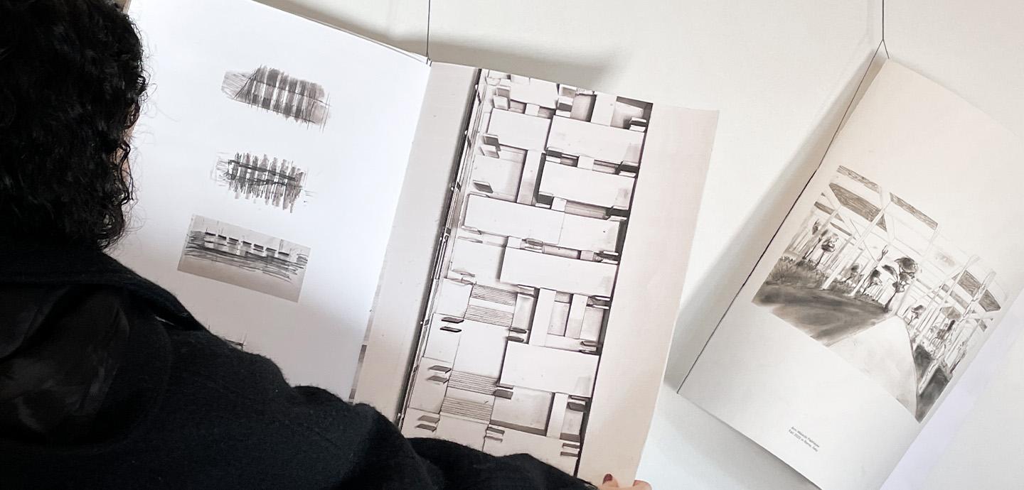 A girl with long dark wavy hair opens a large hanging booklet.