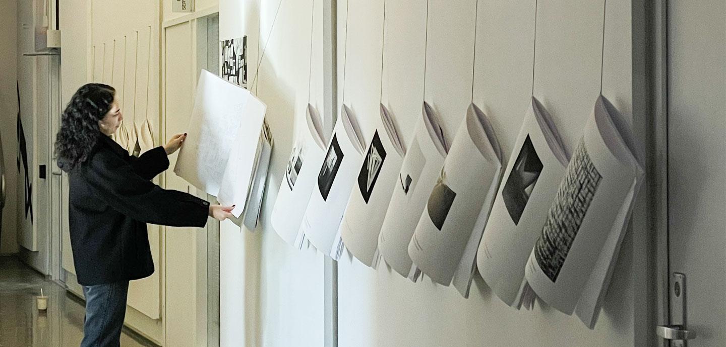 A girl with long dark wavy hair opens a large hanging booklet.