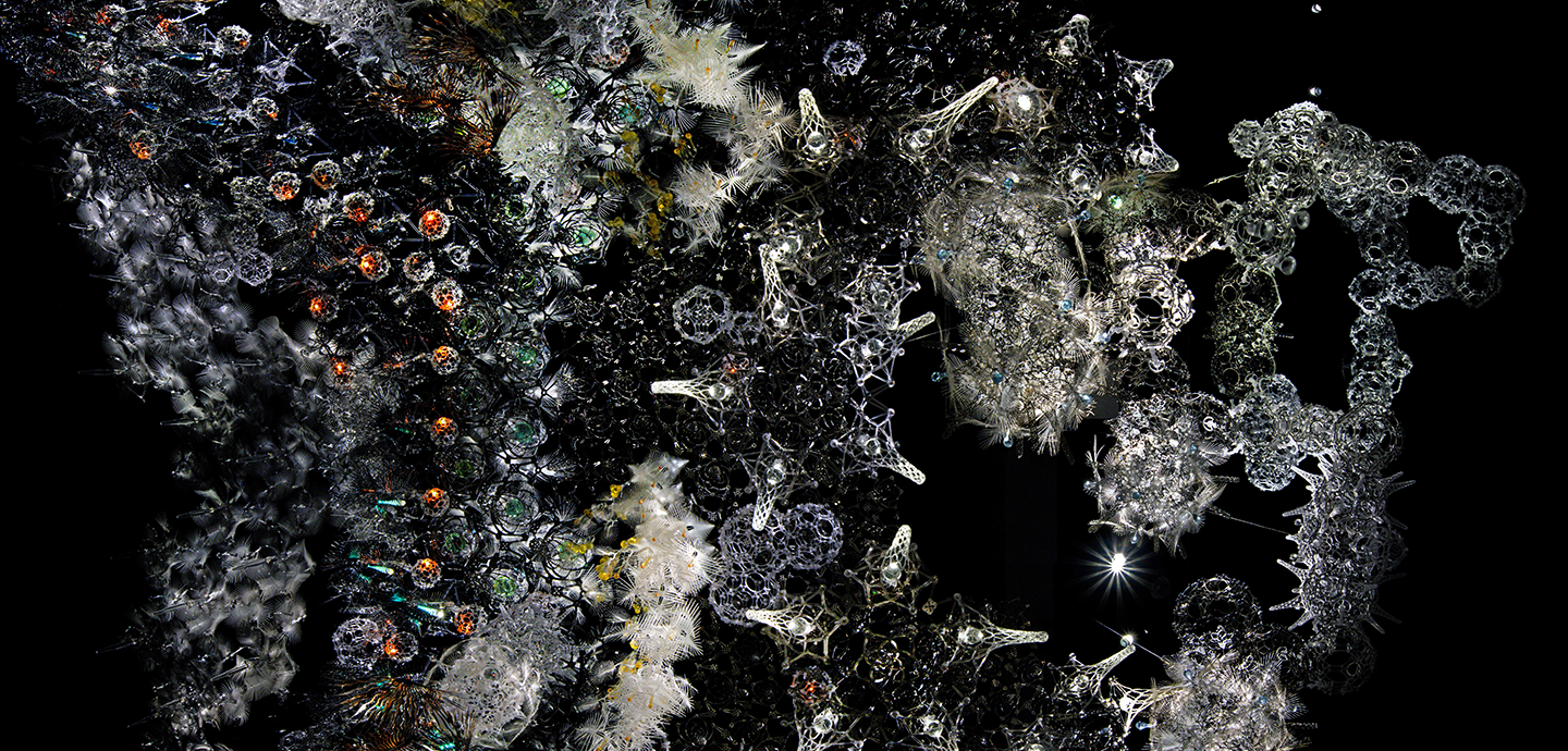 Top view of an installation composed of numerous structures of diferent sizes, shapes and colors - the entire combination resembling a an starry night sky.