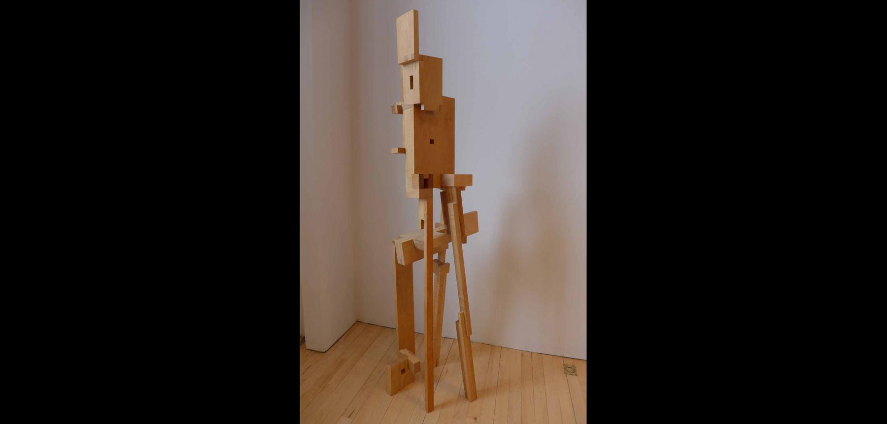Abstract wooden sculpture piece with various sized rectangular pieces put together.