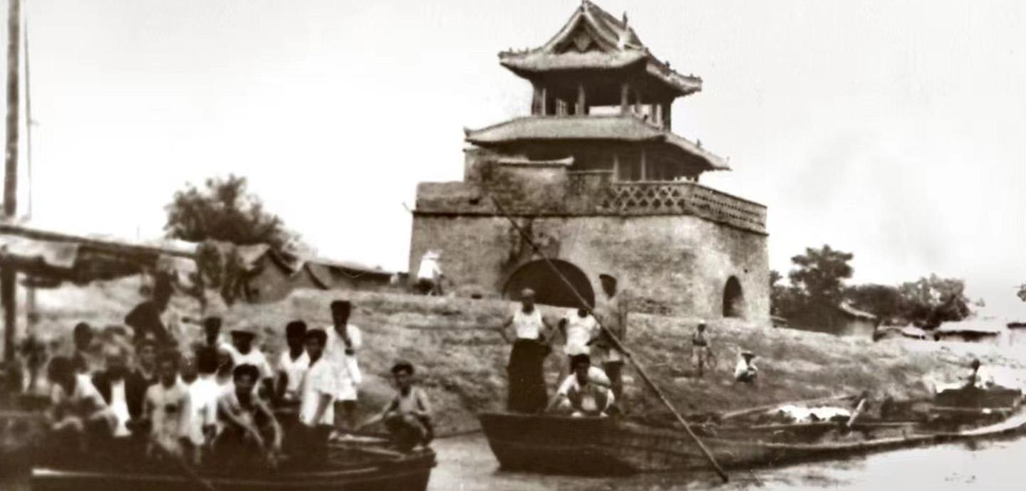 Vintage photograph of building created with Linqing bricks in a traditional design with a canal in the foreground occupied by people in boats.