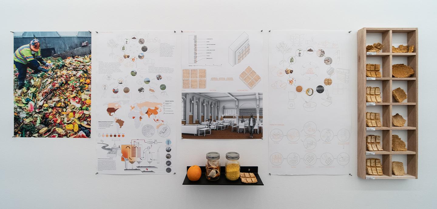 Photos, drawings, and material samples mounted on exhibition wall.