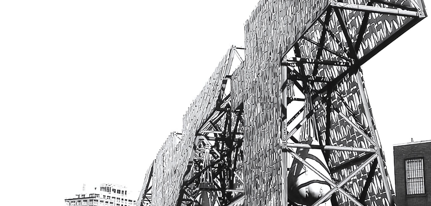 an intricate, large-scale structure featuring a mix of industrial and architectural elements. The structure appears to be composed of metal beams and panels arranged in a complex pattern. The panels have a textured, almost woven appearance, creating a dynamic visual effect. The setting is outdoors, with a partially visible cityscape in the background, including buildings with distinct windows and rooftops. The overall composition conveys a sense of modern architectural design, combining bot