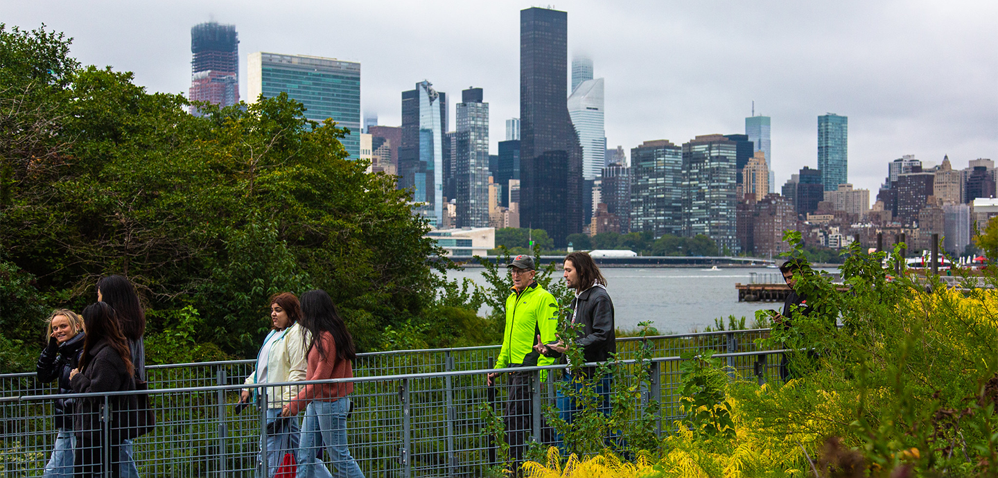 Several people walking down a path with a city skyline in the background.
