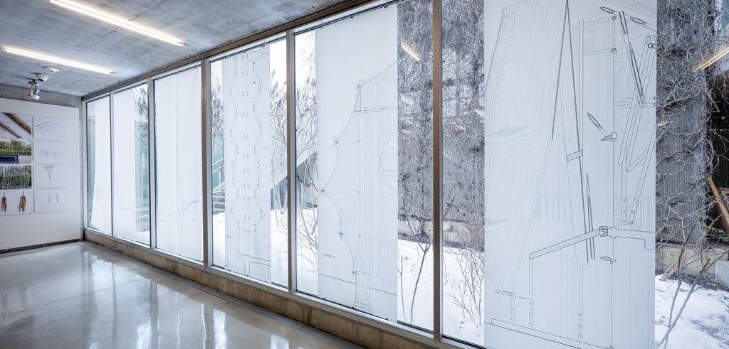 A series of artwork hung on vertical window panes. 