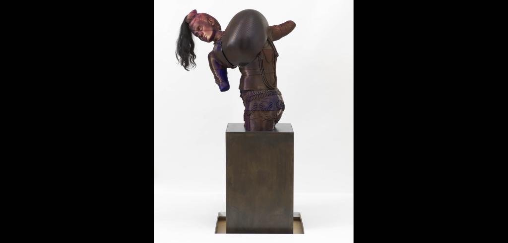 Bust of a figure with long dark hair leaning to the left wearing an intricate outfit carrying a large dome in front of it on a steel pedestal.