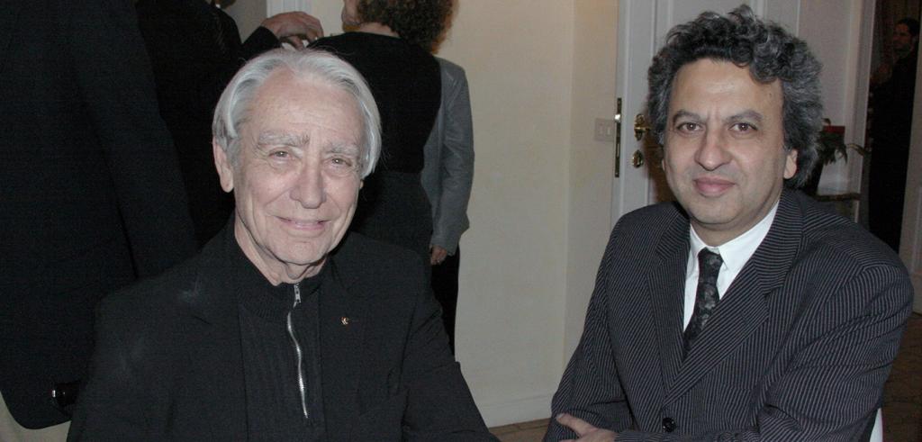 Two men in dark clothing seated at a social gathering.