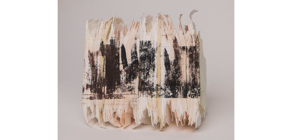 Abstract paper sculpture with black screen print ink on it, photographed in front of a white background.