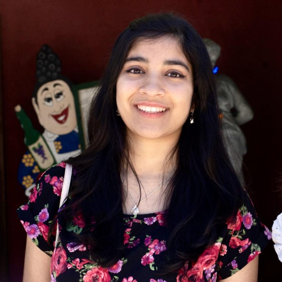 A person with long black hair smiling with a floral shirt.
