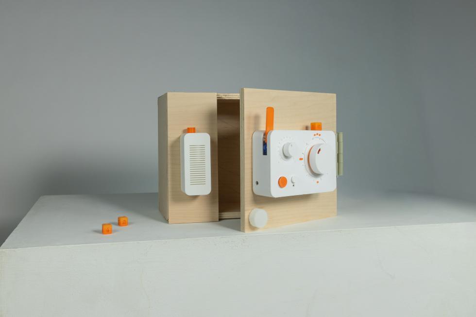 A rectangular device with buttons, rotationg knobs, and small cubic attachable pieces placed on a small cabinet door.