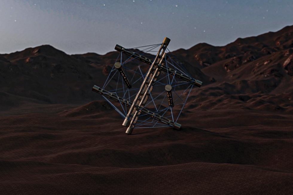 A ball-like geometric structure formed by multiple wires and metal rods tensed together, sitting on red sand desert with mountains on the horizon.