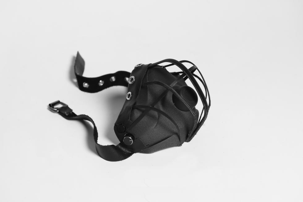 A leather-looking black mask with riveted straps, and a speaker in the place of the mouth. 