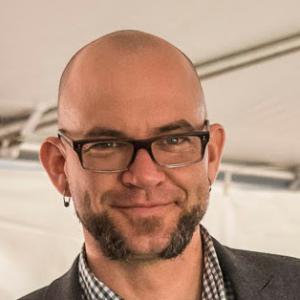 headshot of a bald man with a beard and glasses