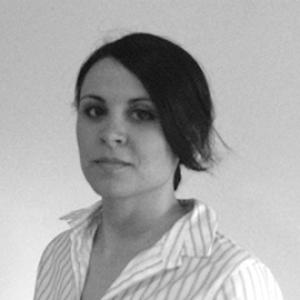 headshot of a young woman with dark hair wearing a white striped shirt in front of a grey background