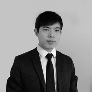 young man with black hair wearing a dark jacket, white shirt, and dark tie