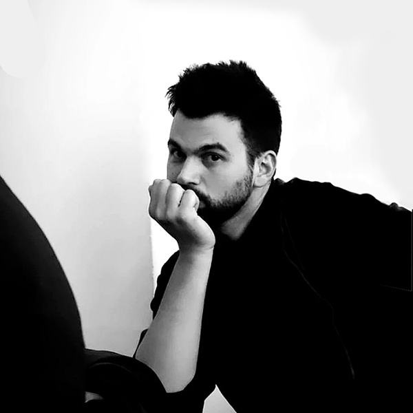 A person wearing all black sitting with their head resting on their hand.